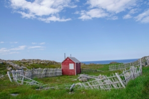 red shed with wrecked fences under blue sky and white clouds during daytime